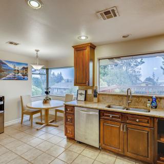 A spacious kitchen with wooden cabinets and a dining area by the window, featuring modern appliances and abundant natural light.