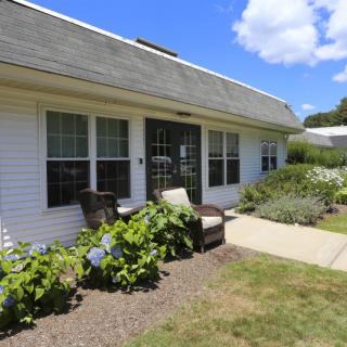 A cozy house with a well-maintained garden and patio under a sunny sky.