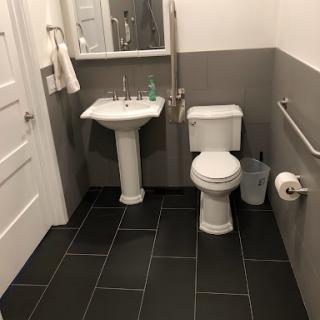 A modern bathroom featuring a toilet and sink with gray tiled flooring.