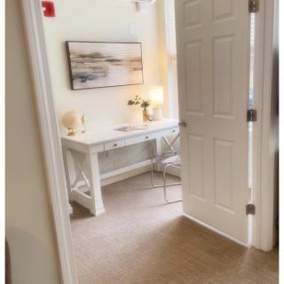A cozy home office setup with a desk, chair, and lamp next to an open door.