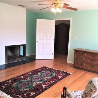 A cozy living room with a fireplace, hardwood floors, and a decorative rug.