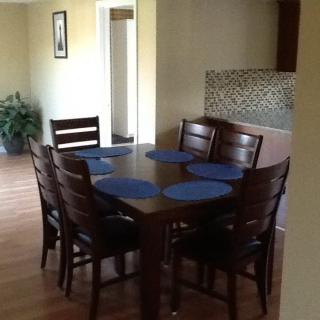 A dining room with a wooden table set for six, featuring blue placemats.