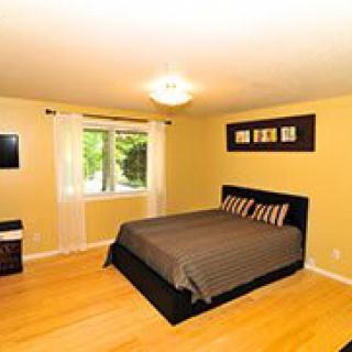 A cozy bedroom with a double bed, decorative pillows, and a window letting in natural light.