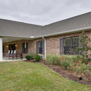 A brick house with a landscaped backyard and a covered patio.