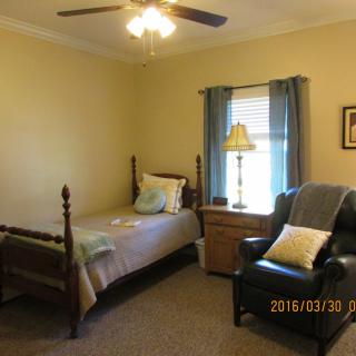 A cozy bedroom with a single bed, armchair, and window with curtains.