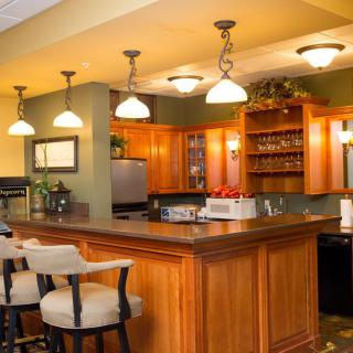 A modern kitchen featuring a wooden bar counter with pendant lighting and sleek wood cabinetry.