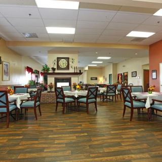 A cozy dining room with neatly arranged tables and chairs, featuring warm decor and lighting.