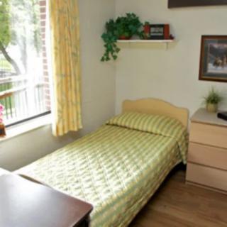 A cozy bedroom with a single bed, dresser, and a window with curtains.