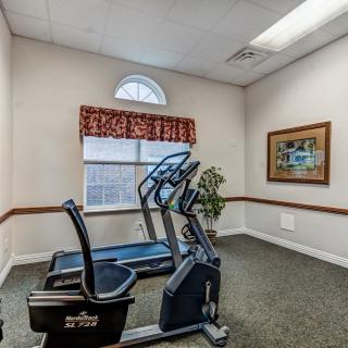 A small fitness room with a treadmill and exercise bike next to a window.