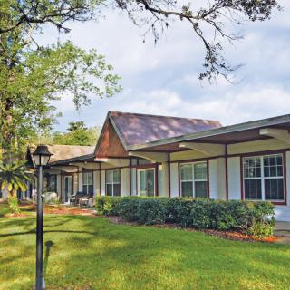 A suburban house with a well-maintained lawn and surrounding trees.