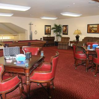 A cozy lounge area featuring red chairs and tables, with artwork on the walls and warm lighting.