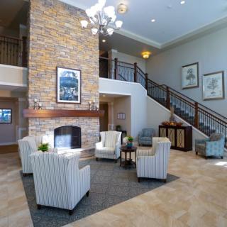 A spacious hotel lobby with a cozy seating area, brick fireplace, and stylish staircase.