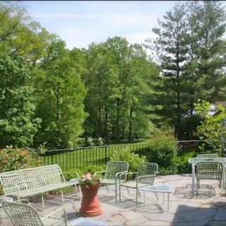 A serene patio with outdoor furniture overlooking a lush garden and trees.