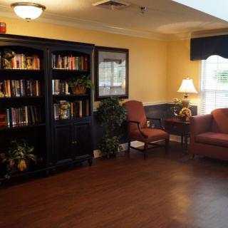 A cozy reading area with a bookshelf, armchair, and a lamp.