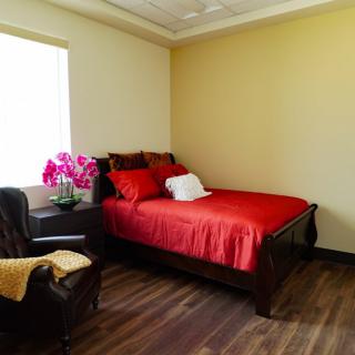 A cozy bedroom with red bedding and a comfortable armchair.