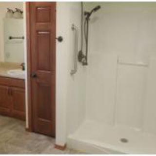 A bathroom featuring a walk-in shower, wooden cabinet, and sink.