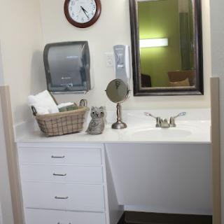 A clean and organized bathroom sink area featuring a mirror, clock, and neatly arranged towels.