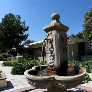 A decorative outdoor fountain with ornate designs in a sunny garden setting.