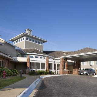 Entrance of a modern healthcare facility with a parking area.