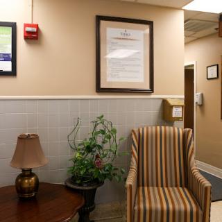 A cozy waiting area featuring a striped chair, lamp, and decorative plant.