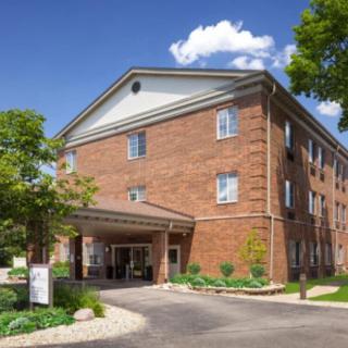 A brick hotel building with an entrance area and surrounding greenery.