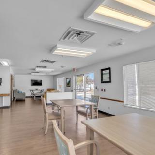 A modern dining area with tables and chairs, featuring bright lighting and a minimalist design.