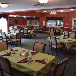 A spacious dining room with elegantly set tables and chairs, featuring a warm interior design.