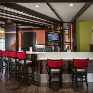 A modern bar interior featuring red chairs and a sleek design.