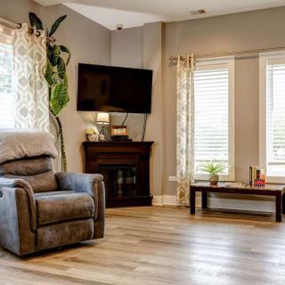 A cozy living room with a recliner, mounted TV, and a corner fireplace.