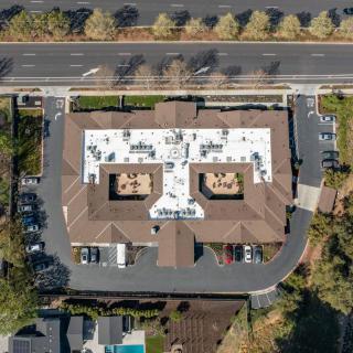 Aerial view of a building with a distinct roof design and surrounding parking area.