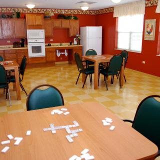A kitchen and dining area with tables and chairs, featuring dominoes on one of the tables.