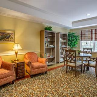 A cozy living room with armchairs, bookshelves, and a table set by the window.