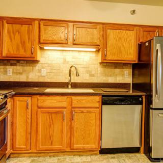 A modern kitchen featuring wooden cabinets, stainless steel appliances, and a stone countertop.