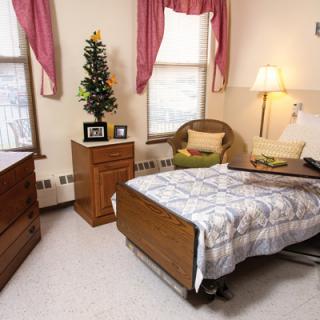 A cozy room featuring a hospital bed, wooden furniture, and warm decor.