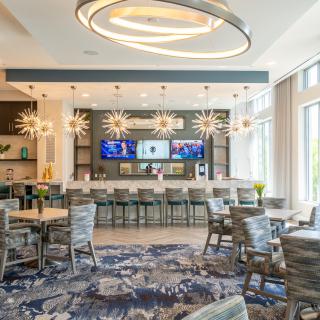 A modern bar and dining area with unique lighting fixtures and multiple televisions.