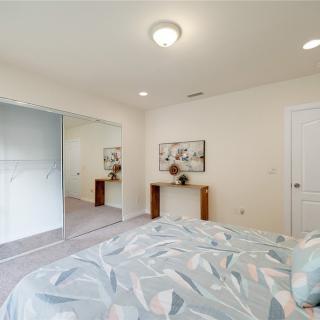 A modern bedroom featuring a cozy bed, mirrored closet doors, and tasteful wall art in soft neutral tones.