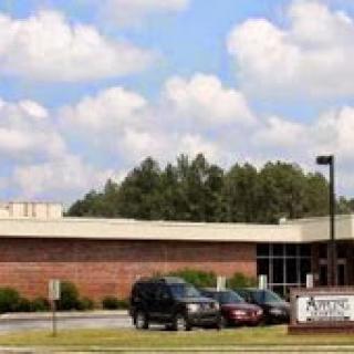 An exterior view of a school building surrounded by lush greenery and a clear sky.