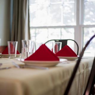 A neatly set dining table with red napkins and glassware.