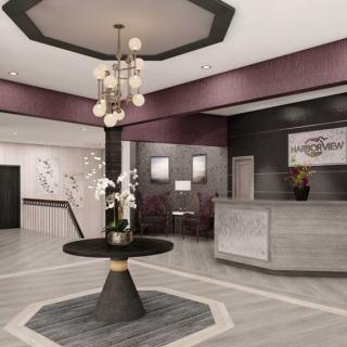 A modern hotel lobby featuring a sleek reception desk and a central table adorned with flowers under a stylish chandelier.