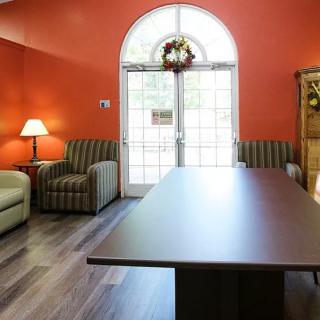 A cozy living room with a large table, comfortable chairs, and a decorative lamp.