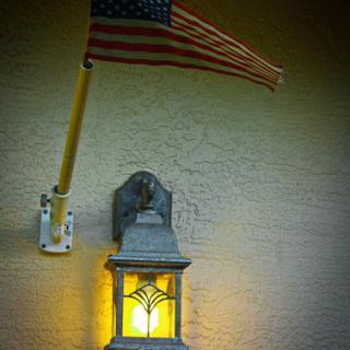 An illuminated lantern beside an American flag, enhancing the charm of the home exterior.