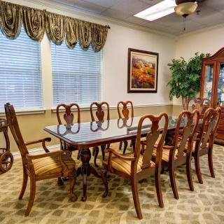 A traditional dining room featuring a large wooden table with matching chairs, elegant drapery, and tasteful decor.
