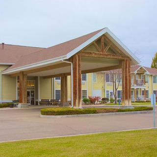 A view of a building with a covered entrance and surrounding landscape.