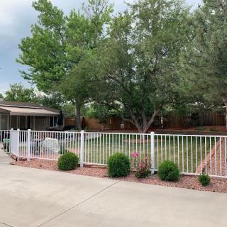 A well-maintained backyard with a white fence, green lawn, and mature trees.