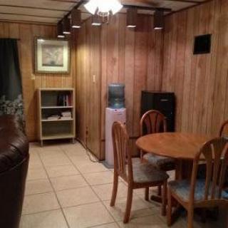 Cozy dining area with wooden walls, a round table, chairs, bookshelf, and water cooler.