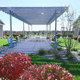A backyard patio with a pergola, surrounded by a landscaped garden.