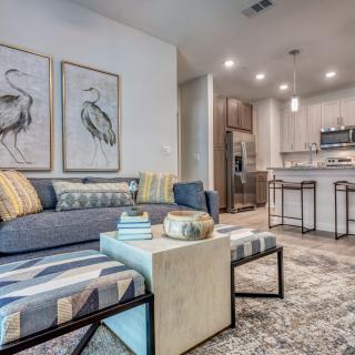 A modern living room and kitchen area featuring stylish artwork, comfortable seating, and contemporary design elements.