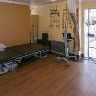 A rehabilitation room equipped with a therapy bed and exercise equipment.