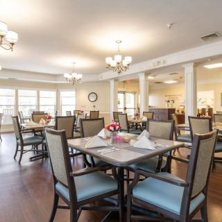 A well-lit dining room with neatly arranged tables and chairs.