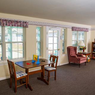 A cozy living room with a table, chairs, and a comfortable armchair near large windows.